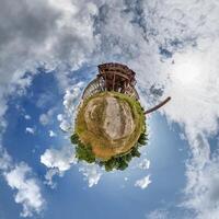 tiny planet in blue sky with clouds of old abandoned ruined church. Transformation of spherical 360 panorama in abstract aerial view. photo