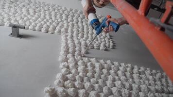 A view of a builder from below, standing on scaffolding, using a foam gun to create a design on a white plastered wall. video