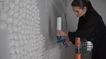 Decorator is using a foam pistol to create three-dimensional decorations on the wall of an institution. video