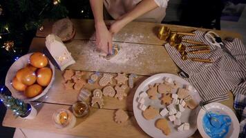 Top view of the pastry chef's work on table at home, surrounded by New Year decorations. She creates classic, traditional ginger cookies, associated with comfort, warmth, and Christmas video