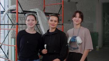 equipe do jovem arquitetos, consistindo do atraente mulheres, é sorridente docemente para Câmera. elas estão às construção site, Onde elas estão supervisionando execução do seus interior Projeto projeto. video