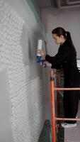 Young woman is arranging and updating the interior design of her home. She creates a unique three-dimensional wall decoration using mounting foam. video