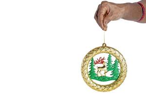 A hand holding a gold ornament with a deer and trees photo