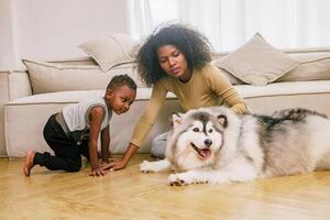 woman and a child are playing with a large dog in a living room photo