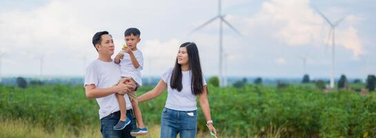 family of four is walking through a field with wind turbines in the background photo