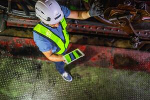 man in a safety vest is looking at a tablet while standing on a platform photo