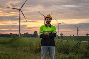 man in a yellow helmet stands in front of a wind farm photo