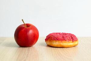 an apple and a donut on the table. concept of choosing healthy food and unhealthy food photo