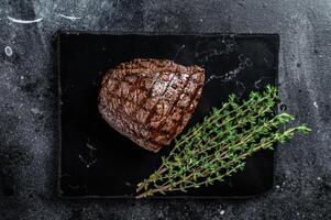 Grilled Rump steak with spices, cooked beef meat. Black background. Top view photo