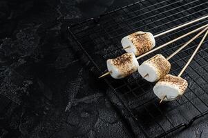 BBQ Grilled Marshmallow on the sticks. Black background. Top view. Copy space photo