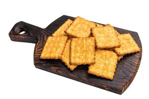 Heap of square salty crackers on wooden board isolated on white background, top view. photo