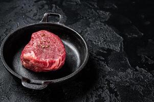Fillet Mignon prime beef steak, raw dry aged marble meat with herbs and spices ready for cooking. Black background. Top view. Space for text photo