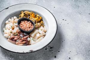 Raw seafood mix in a rustic plate. Gray background. Top view. Copy space photo