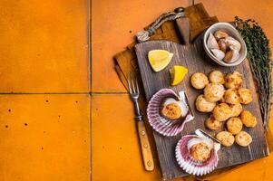 Seared Scallops fillets on a wooden board ready for eat. Orange background. Top view. Copy space photo