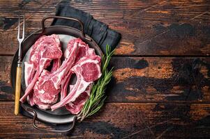 Raw lamb mutton chop steaks, fresh meat cutlets on butcher table. Black background. Top view. Copy space photo