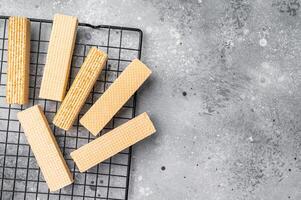 Dry Wafer stick biscuits with vanilla cream on a rack. grey background. top view photo