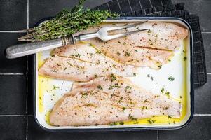Marinated ocean red perch fillet with olive oil, thyme and spices. Black background. Top view photo
