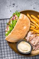 Grilled shawarma sandwich, Doner kebab with grilled meat in pita bread on a plate with french fry. grey background. top view photo
