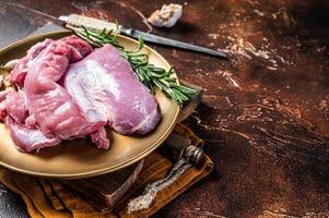 Fresh skinless raw Turkey thigh fillet meat with spices. Dark background. Top view. Space for text photo