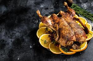 Christmas dinner, baked duck with rosemary and oranges, crispy whole roast duck. Black background. Top view. Copy space photo