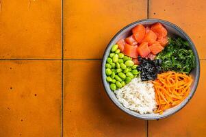 Top view of Poke bowl with Salmon, Edamame and Rice. Orange background. Top view. Copy space photo