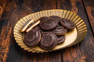 Steel plate with Jaffa Cookies covered with chocolate and filled with jam. Wooden background. top view photo
