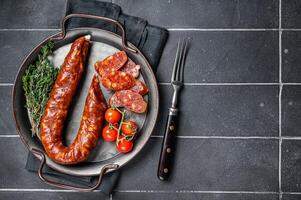 Sliced Chorizo sausage, slices of dry cured pork with herbs and spices. Black background. Top view. Copy space photo