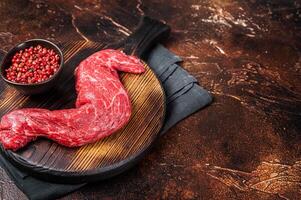 Raw Skirt Machete beef meat steak on wooden board. Dark background. Top view. Copy space photo