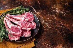 Raw lamb chops, fresh mutton meat cutlets on a ribs. Dark background. Top view. Copy space photo