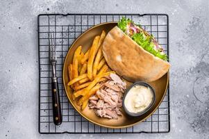 Grilled shawarma sandwich, Doner kebab with grilled meat in pita bread on a plate with french fry. grey background. top view photo