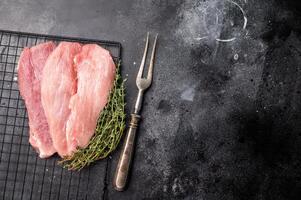 Raw pork fillet meat for schnitzel, steaks on a rack. black background. top view photo