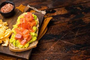 Sandwich with smoked salmon, trout, avocado and red caviar. wooden background. top view photo