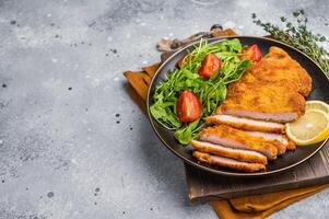 Fried Weiner schnitzel steak, veal breaded meat with salad on a plate. grey background. top view photo