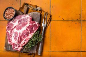 Raw pork steak chops, neck meat with herbs. Orange background. Top view. Copy space photo