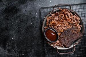 Slow Cooked Pulled Beef, Traditional meat rubbed with spices and smoked in a Texas smoker. Black background. Top view. Copy space photo