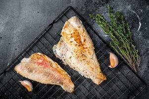 Grilled sea red perch fillet, Snapper fish on a rack. Black background. Top view photo