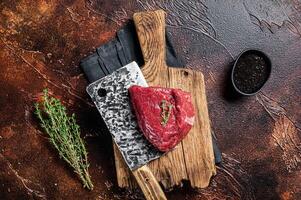 Raw rump steak on a butcher cutting board. Dark background. Top view photo
