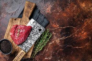 Raw rump steak on a butcher cutting board. Dark background. Top view. Copy space photo