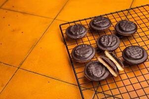 Fresh cooked Jaffa Cookies covered with chocolate and filled with jam on rack. orange background. top view photo