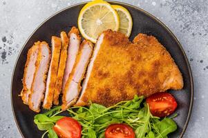 Fried Weiner schnitzel steak, veal breaded meat with salad on a plate. grey background. top view photo