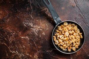 Fried peeled Shrimps prawns with garlic, olive oil in a skillet. Dark background. top view. copy space photo