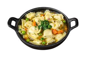 Broth soup with ravioli dumplings pasta in a pan. Isolated on white background. Top view. photo