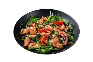 Salmon salad with fish slices, arugula, tomato and green vegetables. Isolated on white background. Top view. photo