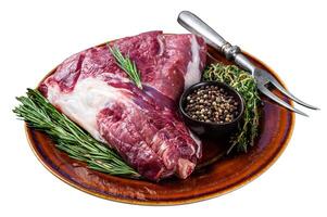Uncooked Raw goat thigh or leg with rosemary and thyme in rustic plate. Isolated on white background. Top view. photo