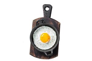 Salted and spiced fried egg in pan with tomatoes, thyme and bacon. Isolated, white background. photo