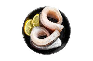 Fresh raw hake fish fillet in a pan with pepper and lemon. Isolate, white background. photo