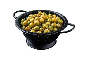 Fresh green gooseberries in a colander. Isolated on white background, top view. photo