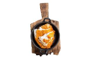 Roasted tilapia fillet in a skillet with breadcrumbs. Isolated, white background. photo