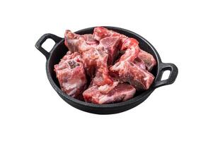 Raw diced meat cubes with bone in a pan. Isolated on white background. Top view. photo