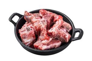 Raw diced meat cubes with bone in a pan. Isolated, white background. photo